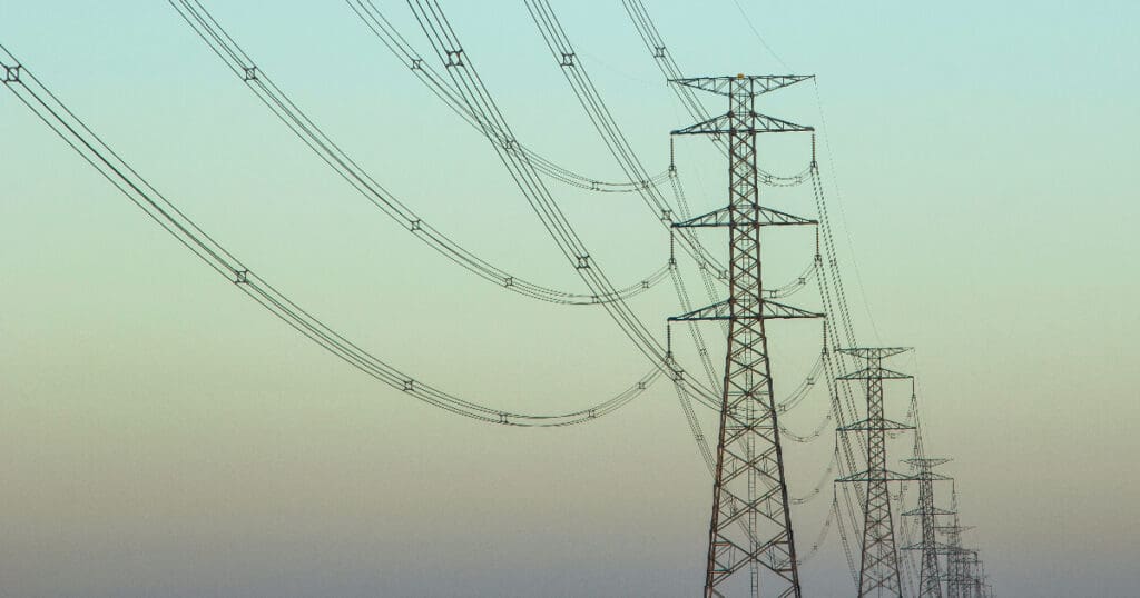 a row of overhead powerlines suspended from a line of towers that disappears into the distance